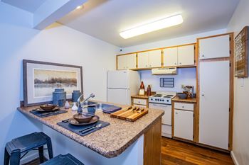 A kitchen with a table set for two and a painting on the wall.
